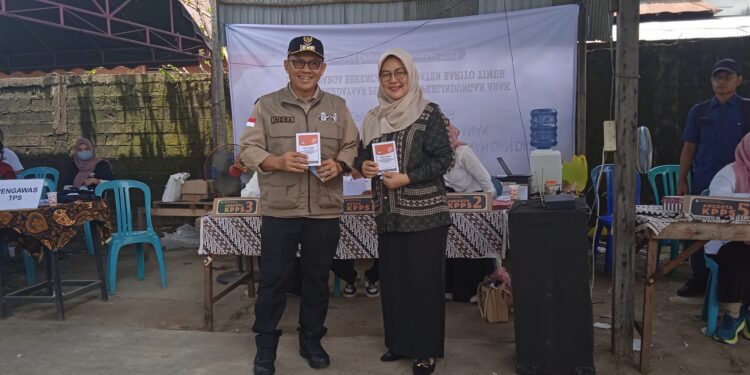 Serasi, Pj Bupati Bartim Didampingi Istri Nyoblos di TPS 01 Tamiang Layang