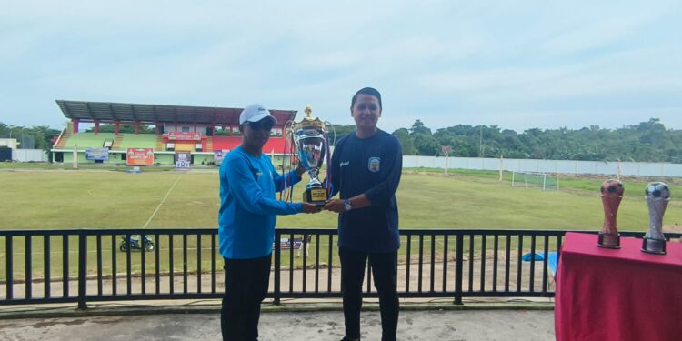 Bupati Murung Raya, Heriyus (kiri), menyerahkan trophy untuk diperebutkan dalam Turnamen Sepak Bola Bupati Cup I HEBAT 2025 di Stadion Dr. Willy M. Yoseph, Puruk Cahu, Senin (10/11/2025).