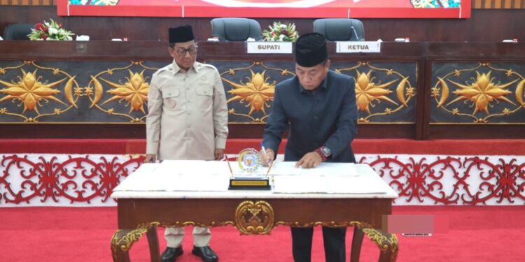 Ketua DPRD Murung Raya, Rumiadi, bersama Bupati Murung Raya, Heriyus, menandatangani berita acara persetujuan bersama dua Raperda dalam Sidang Paripurna ke-10 Masa Sidang III Tahun 2025 di Ruang Rapat Paripurna DPRD Murung Raya, Jumat (19/12/2025).