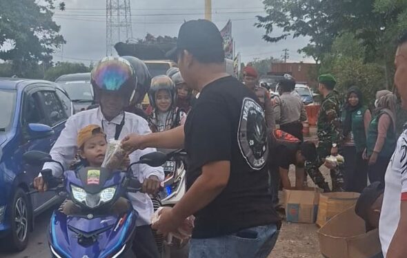 Jajaran personel Satresnarkoba, Lantas, dan gabungan Tim Pelayanan Operasi Lilin Telabang 2025 membagikan snack roti dan minuman untuk jemaah Guru Sekumpul yang melintas, Sabtu (27/12/2025).