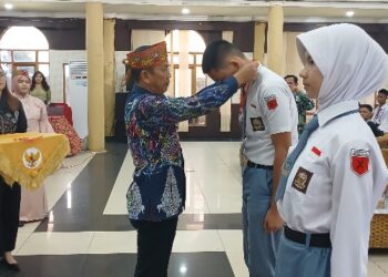 Asisten II Setda Bartim, Amrullah, mengalungkan tanda peserta seleksi Paskibraka Barito Timur, Selasa (21/4/2026).