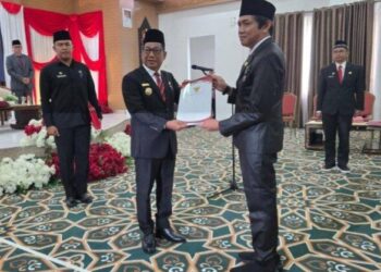 Bupati Murung Raya, Heriyus, menyerahkan SK kepada Kepala Disdukcapil, Gema Topandas, dalam prosesi pelantikan.