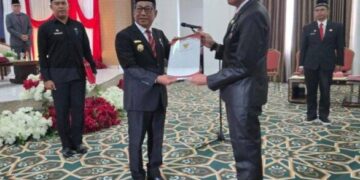 Bupati Murung Raya, Heriyus, menyerahkan SK kepada Kepala Disdukcapil, Gema Topandas, dalam prosesi pelantikan.