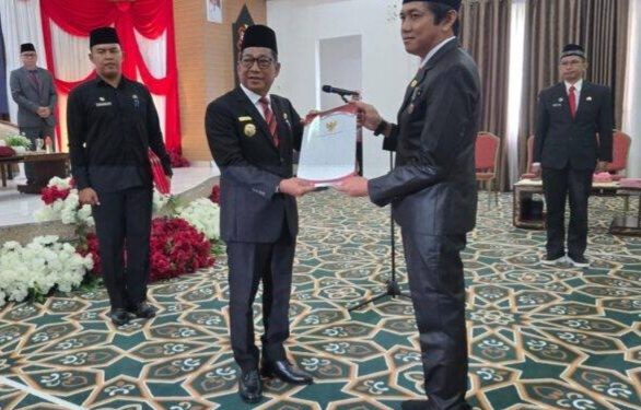 Bupati Murung Raya, Heriyus, menyerahkan SK kepada Kepala Disdukcapil, Gema Topandas, dalam prosesi pelantikan.