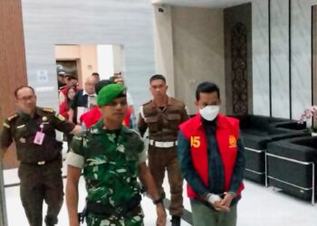 Tersangka korupsi zirkon menggunakan baju tahanan kejaksaan saat digiring menuju mobil tahanan. (Ist)