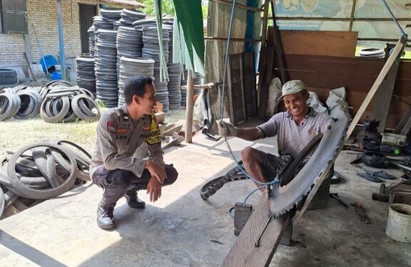Bhabinkamtibmas Polsek Bukit Batu, Aipda Alon, bercengkrama dengan pengrajin ban bekas, Rabu (10/6/2026).