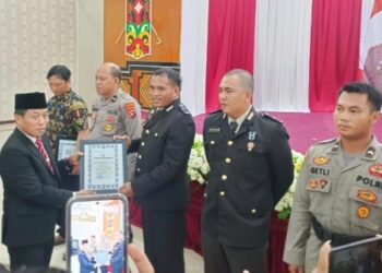 Ketua DPRD Kabupaten Murung Raya, Rumiadi, menyerahkan penghargaan pada momen Hari Bhayangkara ke-80.