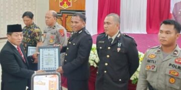 Ketua DPRD Kabupaten Murung Raya, Rumiadi, menyerahkan penghargaan pada momen Hari Bhayangkara ke-80.