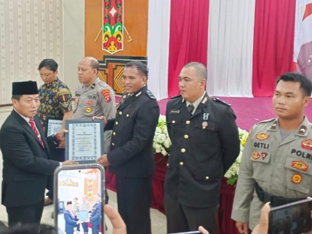 Ketua DPRD Kabupaten Murung Raya, Rumiadi, menyerahkan penghargaan pada momen Hari Bhayangkara ke-80.