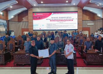 Wakil Ketua I DPRD Kabupaten Kapuas Yohanes, menyerahkan dokumen persetujuan kepada Wakil Bupati Kapuas Dodo dalam Paripurna DPRD Kabupaten Kapuas, Rabu (22/7/2026). (ist)
