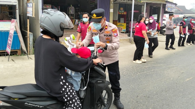 Kapolsek Dusun Tengah IPTU Stefanus Rantealo, S.H., M.M., secara langsung memasangkan masker untuk anak dari pengendara yang melintas, Sabtu (5/9/2026).