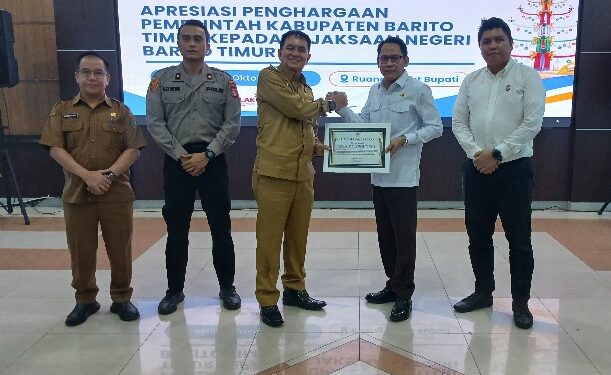 Bupati Barito Timur, M. Yamin menyerahkan penghargaan yang diterima Kajari Barito Timur Abdul Halim, Senin (19/10/2026).